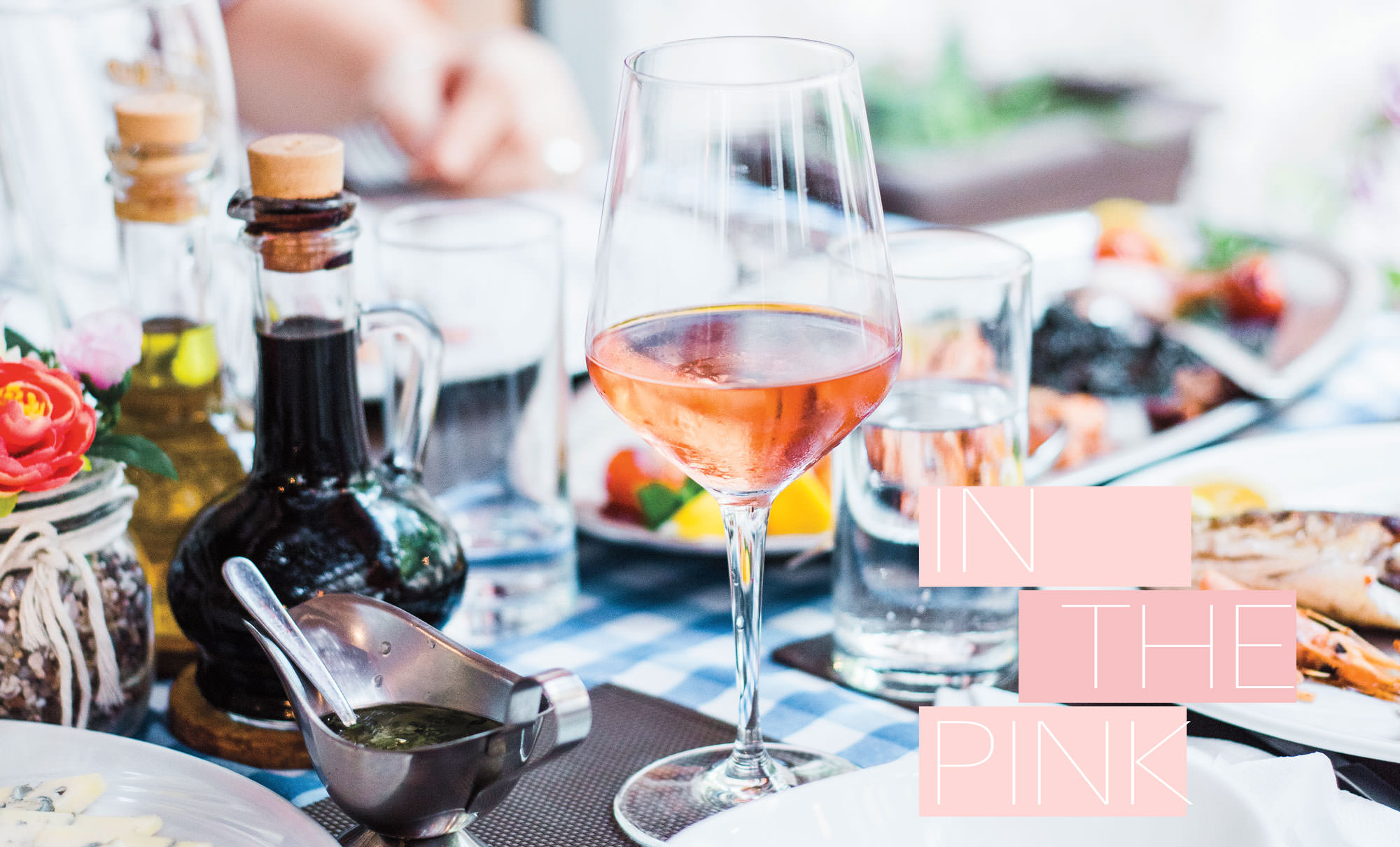 Glass of rosé wine on a dining table with different foods